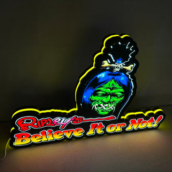 Neon sign with a cartoon character and 'Ripley's Believe It or Not!' text on a dark background